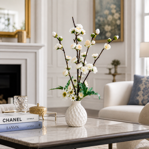 White vase with flowers on a coffee table in a living room setting