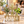 Three glass bottle vases in a natural-tone Home holder with flowers and greenery