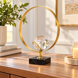 Gold-tone ring and clear crystal ball table sculpture on a black base