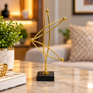 Small gold abstract tabletop statue styled beside books and plants